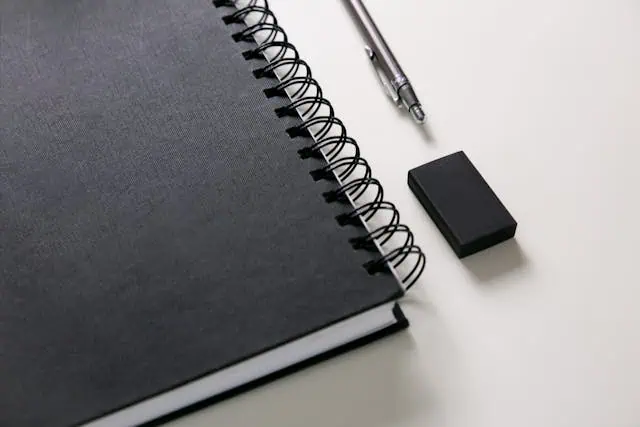 Pen and eraser lying next to a notebook