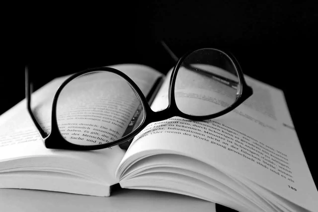 Black-framed wayfarer eyeglasses on a book.